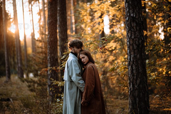 Beautiful fashionable couple in love in the forest at sunset in autumn