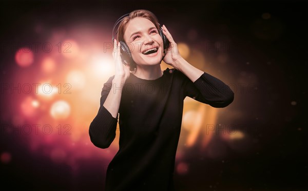 Image of a girl in a black dress with headphones in a nightclub. Party concept.