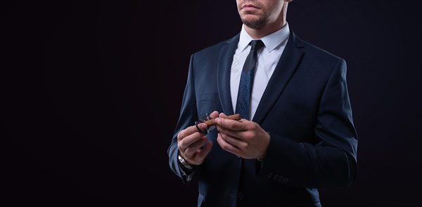 Image of an adult stylish man in a suit with a cigar. Cigar clubs concept.