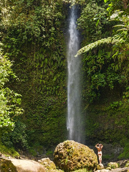 Young woman next to a rock at the Cascada Hola Vida waterfall in the Amazon rainforest