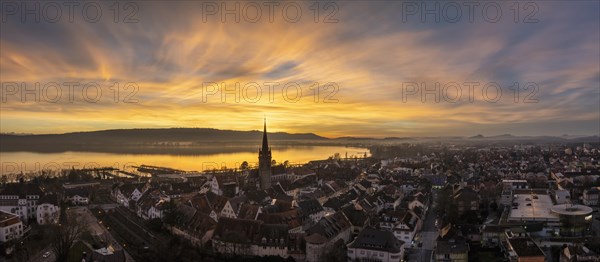 Aerial panorama of an atmospheric sunset over the old town of Radolfzell on Lake Constance with the cathedral tower