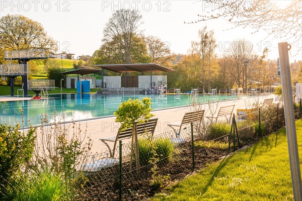 Empty outdoor pool with wooden benches and a fence in the beautiful evening light