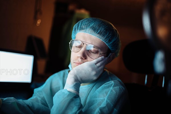 A tired young surgeon falls asleep in the resident's room after hours of complex surgery