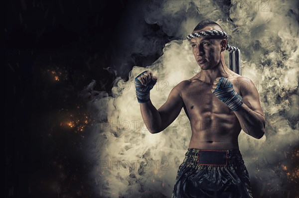 Portrait of a boxer of mixed martial arts standing on the background of smoke and fire. The concept of sports