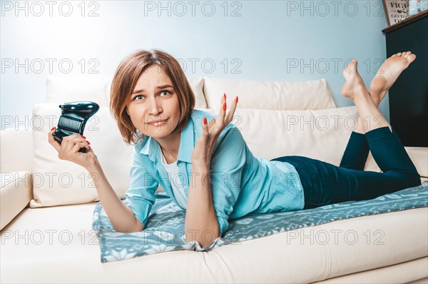 Girl with a joystick in her hands lies on the couch and plays a computer game. ESports concept.