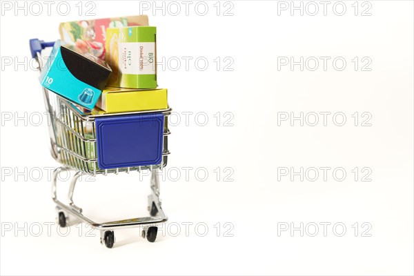 Shopping cart full of boxes of grocery items isolated on a white background