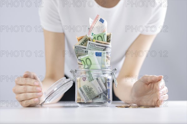 The woman carefully surrounded her piggy bank with her hands. The concept of thrift