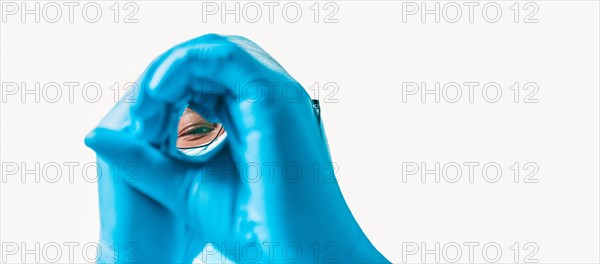 Portrait of a doctor on a white background. He is looking through his hands. Medicine concept.