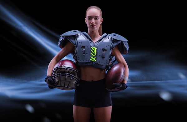 Portrait of a sportive girl in the uniform of an American football team player. Sports concept. Futuristic background.