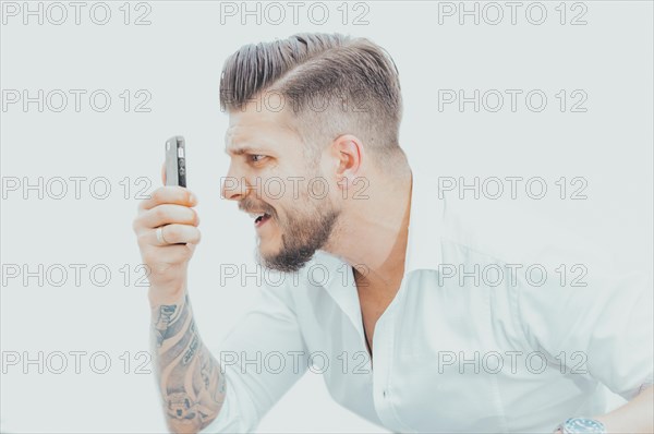 Man in a shirt looks at the smartphone screen in surprise. Concept of unsuccessful betting on games