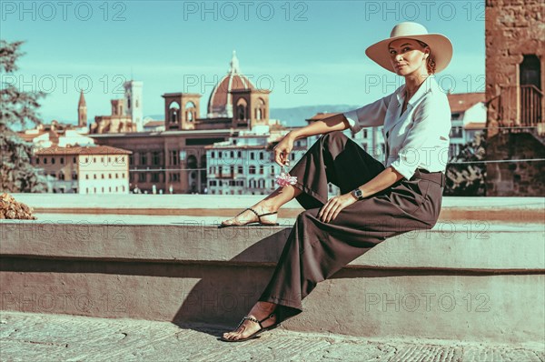 Portrait of a charming girl sitting near a fountain in Florence. View of Santa Maria del Fiore. Tourism concept. Italy.