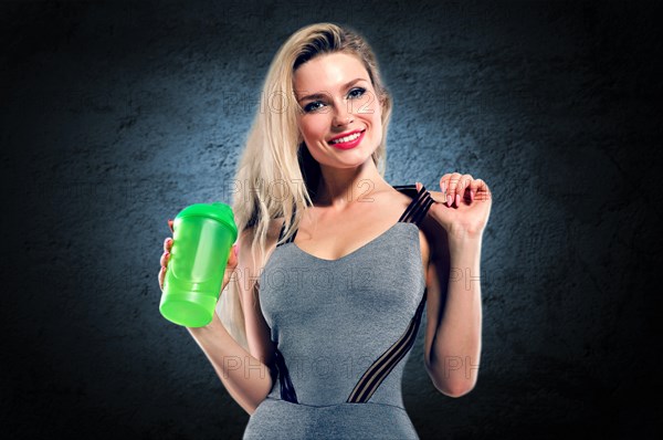 Charming model posing in studio with shaker in hands.