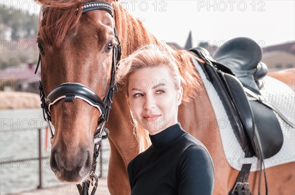 Beautiful stylish woman walking with a horse in a country club. Equestrian sport