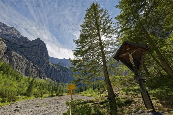 An idyllic mountain landscape with signposts and a wooden cross under a clear blue sky