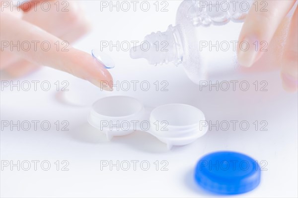 Woman pours liquid on a lens for the eyes. Ophthalmology concept.