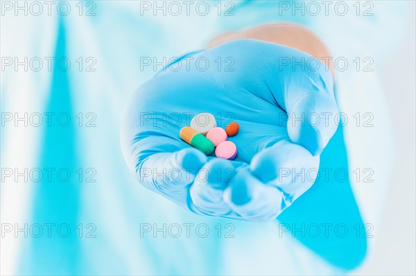 The doctor holds out pills lying on a blue glove. Medical concept.