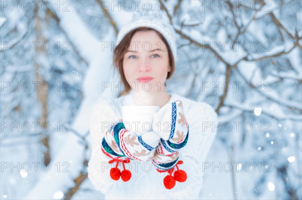 Portrait of a charming girl who holds a mug of hot drink in her hands. Concept of Christmas