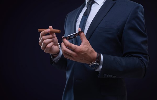 Image of an adult stylish man in a suit with a cigar. Cigar clubs concept.