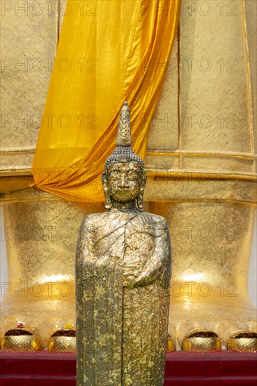 Buddha figure decorated with gold leaf in front of a 32 metre high standing Buddha statue