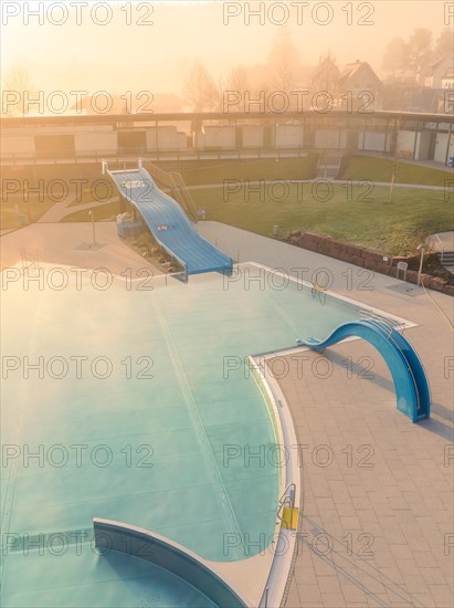 Inviting outdoor pool with slide taken from the air in bright sunshine