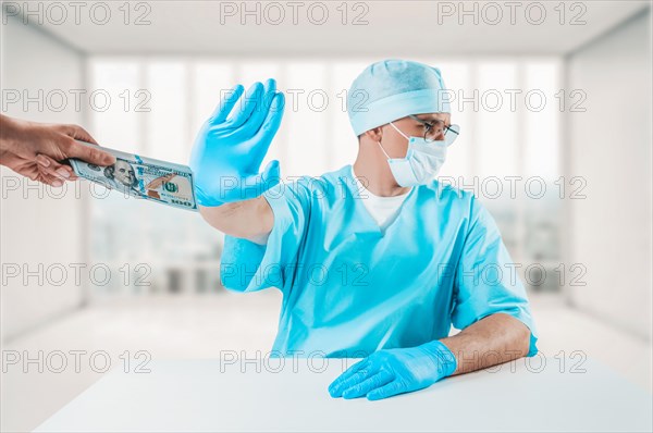 The doctor sits at his desk and refuses a bundle of hundred-dollar bills. Honest medicine concept.