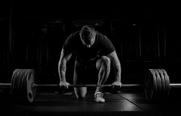 Professional athlete bent over the barbell and is preparing to lift a very heavy weight. Front view