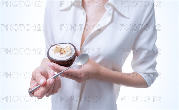 Woman posing in studio with natural coconuts in which dessert is served. Organic food.