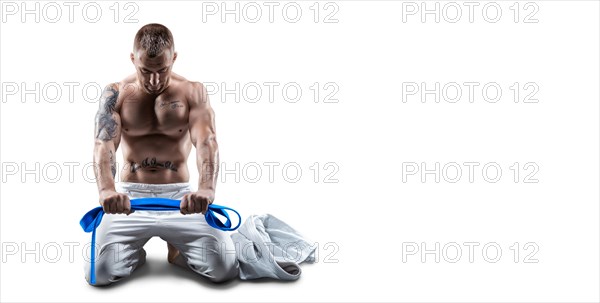 Professional athlete sits in the gym in a kimono with a blue belt. Concept of karate