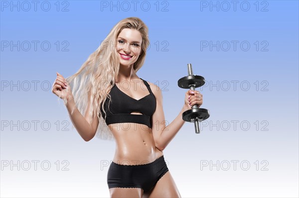 Beautiful athlete posing with a dumbbell in the studio.