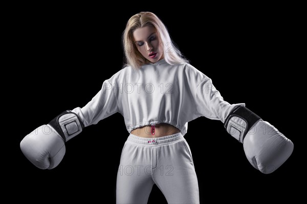 Charming girl in a white sweatshirt posing with huge white gloves. The concept of sports