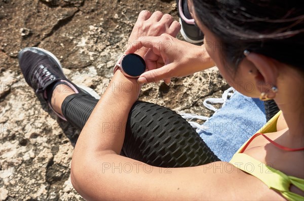 Woman sitting outdoors checking her smartwatch