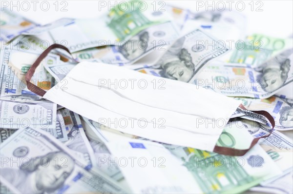 Medical mask rests on one hundred dollar bills. The concept of an epidemic