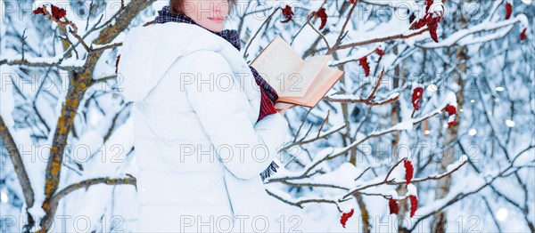 No name portrait of a charming girl who reads a book in the winter forest. Concept of Christmas