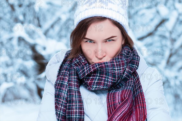 Portrait of a charming woman with a displeased expression on the background of snowy trees. Christmas holidays concept.