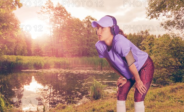 Portrait of a beautiful girl running in a sunny park in headphones with a smartphone. Music apps concept.