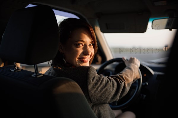 Young beautiful smiling female taxi driver in a jacket greets passengers in a friendly manner