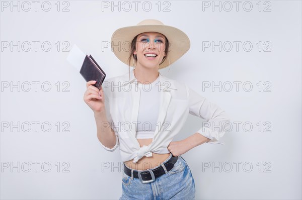 Beautiful girl posing on a white background in a yellow hat with a passport and boarding pass. Tourism concept.