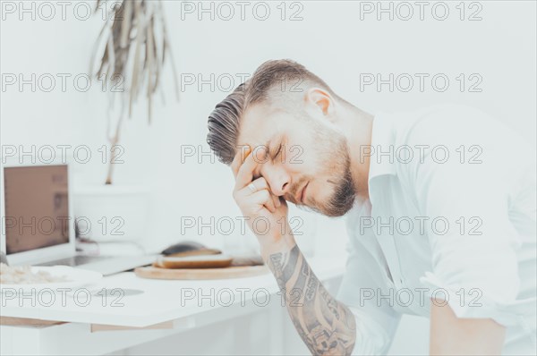 The man in the shirt is very upset by the unpleasant news. He tiredly supported his head and closed his eyes. The concept of disappointment