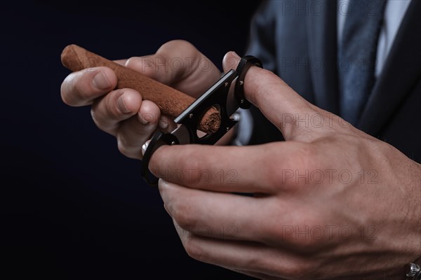 Image of hands holding a guillotine and a cigar. Cigar clubs concept.