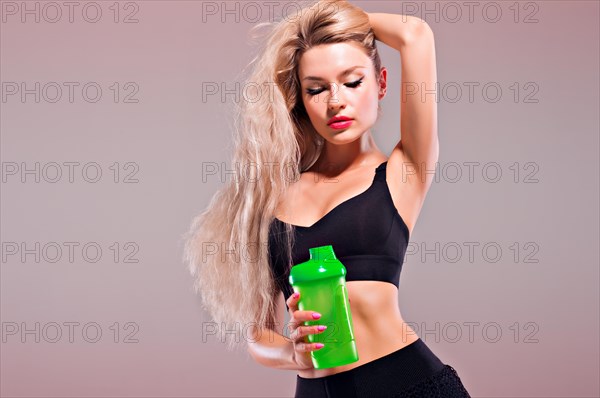 Charming girl with shaker in hands posing in studio.