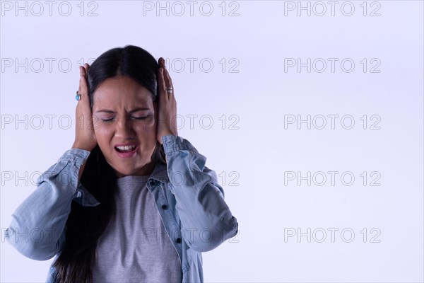 Latin Woman plugging ears with hands does not wanting to listen. Copy space. Portrait isolated on white background