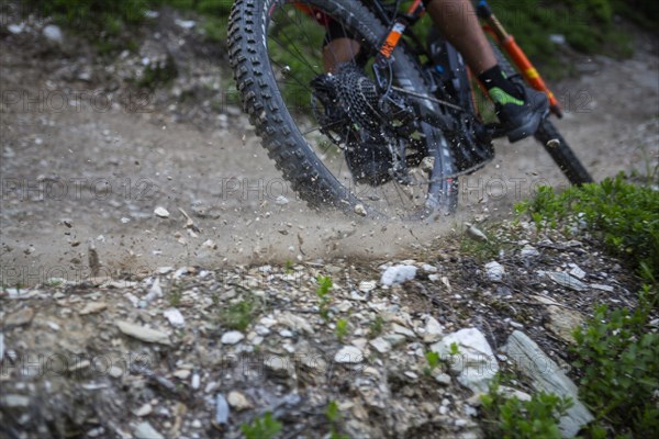 A mountain bike tyre that drifts and throws gravel into the air on the trail