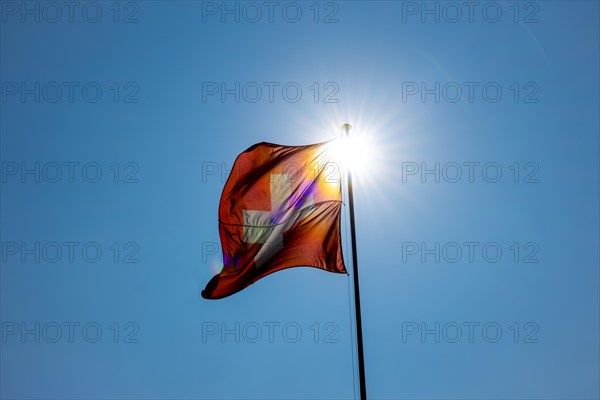 Beautiful Swiss Flag Against Blue Clear Sky and Sunbeam in a Windy Day in Switzerland
