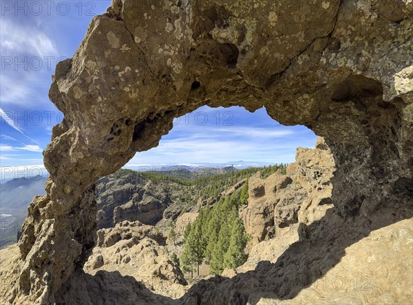 View through a rock arch to Roque Nublo and the Teide mountain peak on the neighbouring island of Tenerife