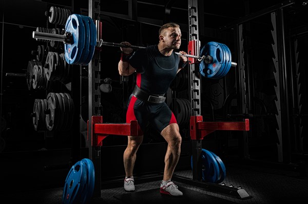 The weightlifter is preparing to lift a very heavy barbell. He exhales breathlessly and strains as much as possible before performing the exercise