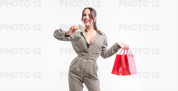 Charming brunette posing in the studio with red packages and a bank card. Gift concept. Shopping before the holidays. White background.