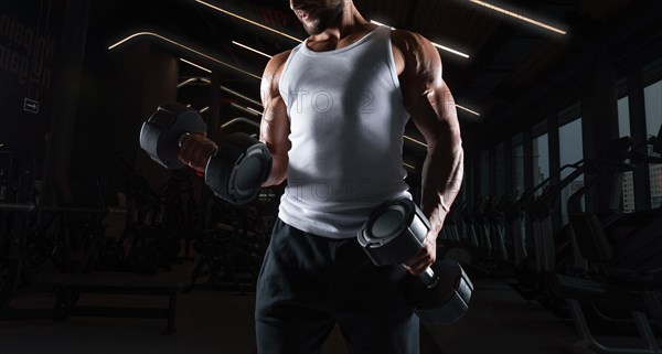 Image of a muscular guy in a white jersey with sports equipment. Gym. Fitness concept