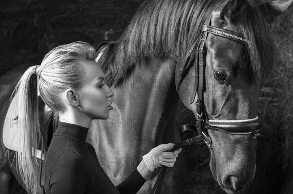 Stunning blonde posing with a thoroughbred horse. Ranch vacation concept.