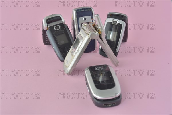 Closed old flip phones with metallic details presented on a solid pink background