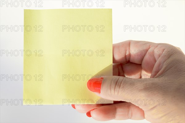 Woman's hand with painted nails holding blank letter paper on pure white background